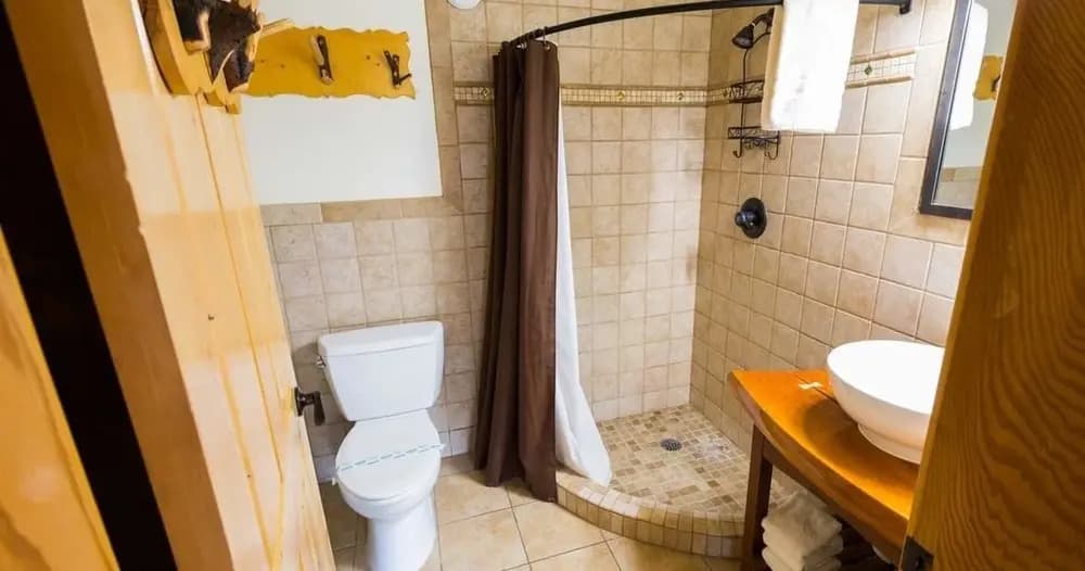 A modern bathroom featuring a shower, toilet, and sink with wooden accents.