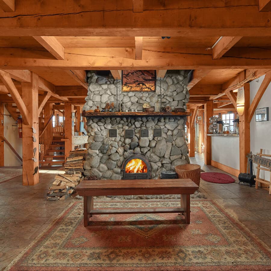 A cozy living space featuring a stone fireplace surrounded by wooden beams and furniture.