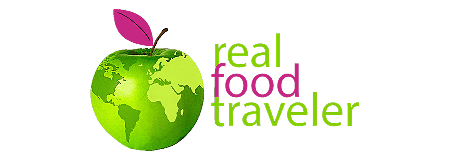 Logo of "Real Food Traveler" featuring a green apple with a world map and a pink leaf.
